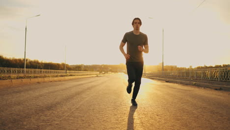 Un-Joven-Deportista-Está-Entrenando-Solo-Por-La-Mañana-Corriendo-En-La-Carretera-En-Un-Clima-Soleado-Para-Mantenerse-En-Forma